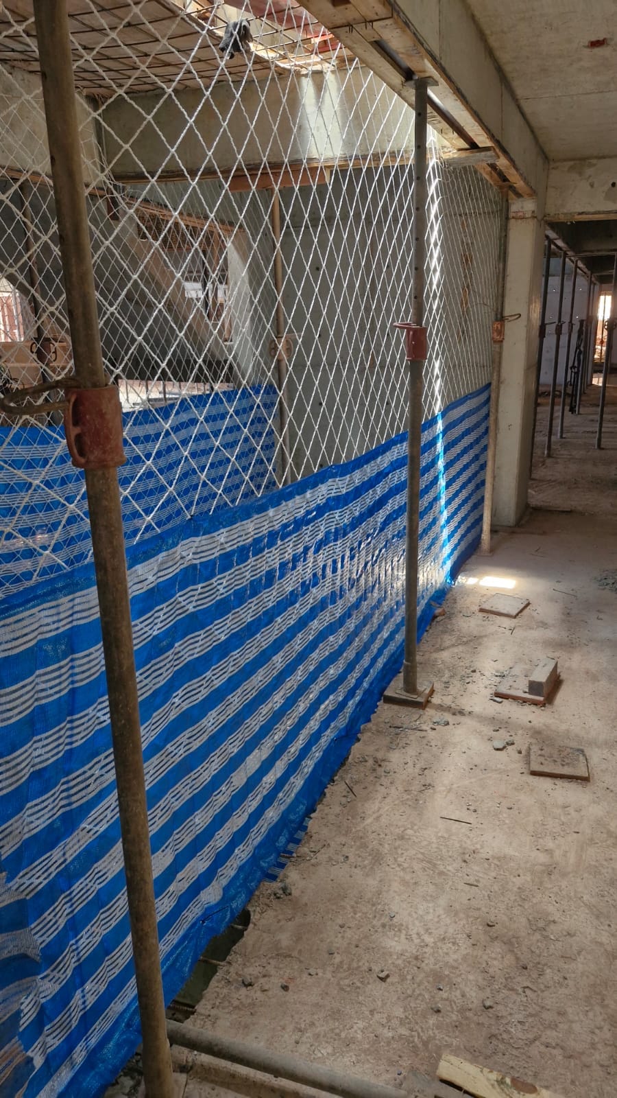 Rede de proteção com tela azul de contenção instalada em corredor interno de obra