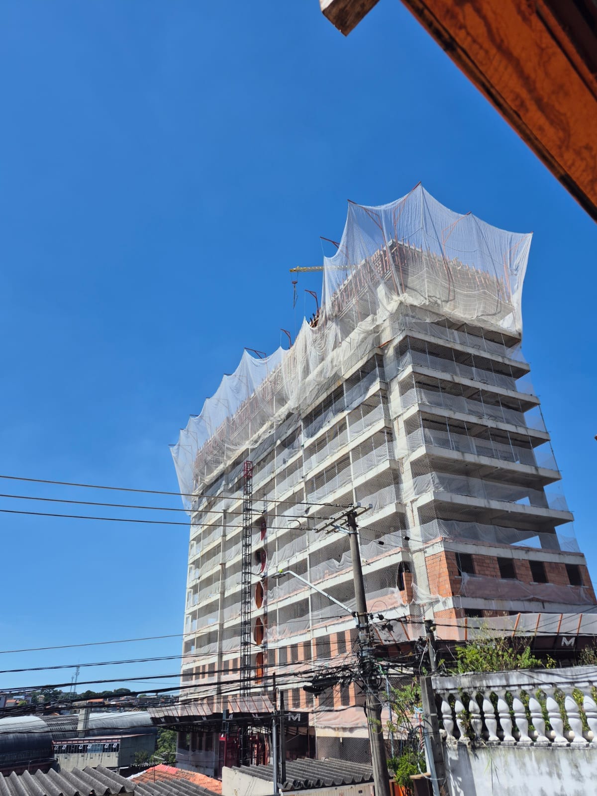 Prédio em construção com sistema SLQA de rede de proteção cobrindo o topo da fachada