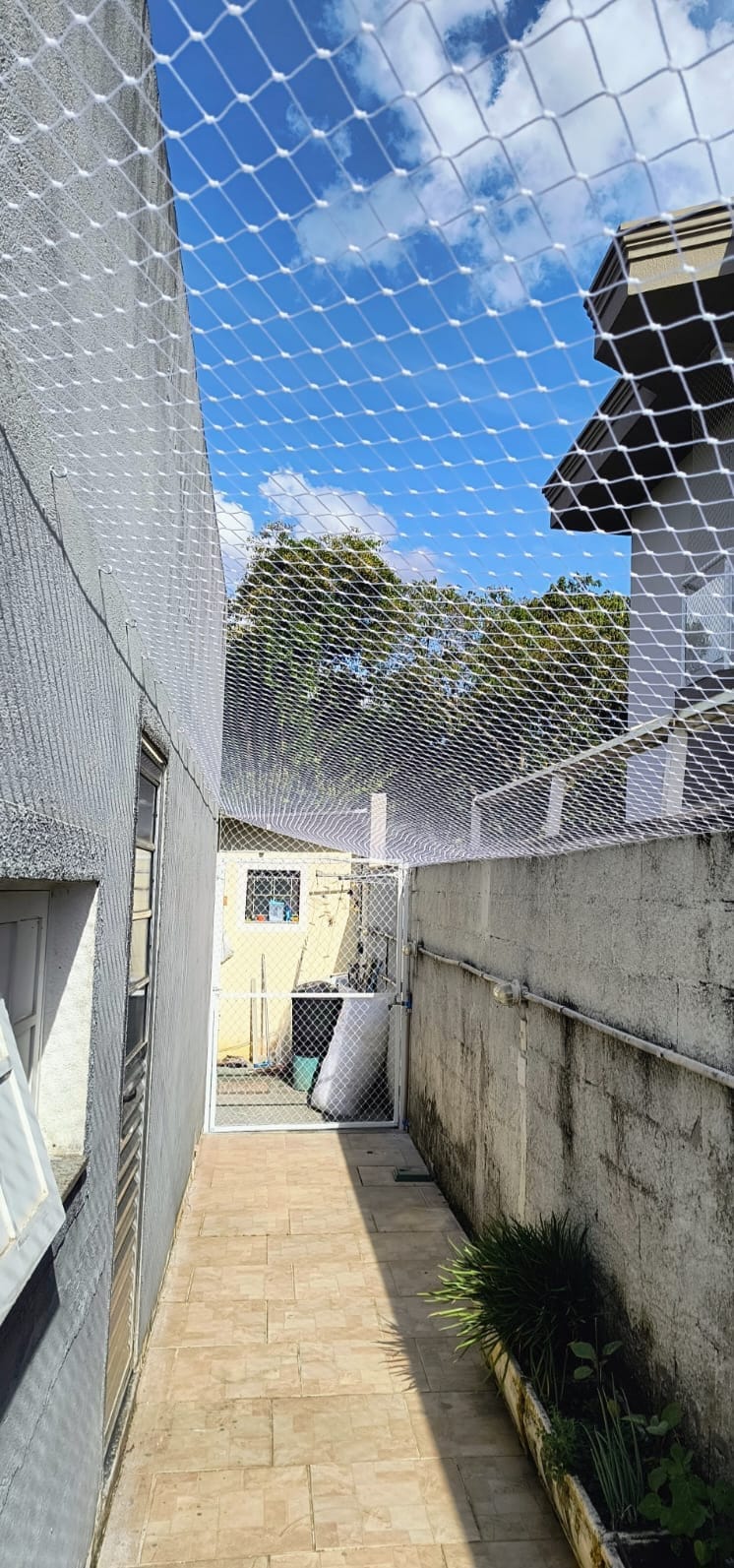 Rede de proteção instalada sobre corredor externo entre duas casas